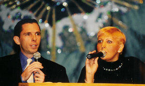 Two people speaking into microphones on a stage