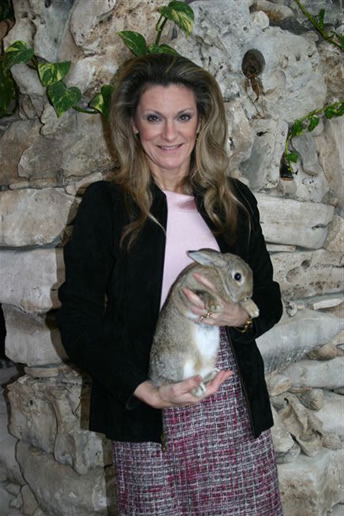 Sherry Greiner holding a large rabbit beside a stone wall