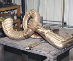 Metal casting of the curled scroll resting on a foundry workbench