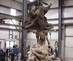 Unfinished horse-and-rider sculpture on its swirling base in the foundry