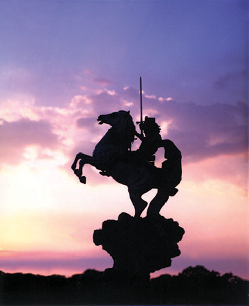 Silhouette of The Coming King® mounted rider against a pink and purple sunset