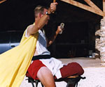 Costumed model on a saddle raising one arm while yellow fabric trails behind him