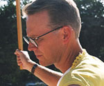 Profile of a costumed model wearing glasses and holding a vertical prop