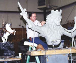 Artist working at the horse-and-rider model from a raised platform