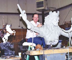 Artist standing behind the sculpture model with its raised sword arm