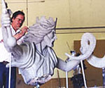 Close view of the artist behind the rider's raised arm and flowing clay cloak