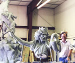 Artist standing to the right of the horse-and-rider model in the workshop