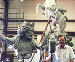 Artist kneeling beside the rider's extended arm and cloak