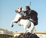 Low-angle view of The Coming King® showing the rider, flowing cloak and white horse