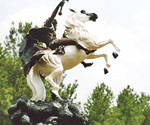 Low-angle view of The Coming King® with a white horse, dark rider and raised sword