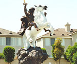 Low-angle view of The Coming King® with a white horse, dark rider and raised sword