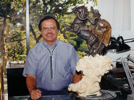 Artist beside a small mounted-rider model in front of the larger sculpture