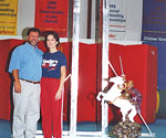 Two visitors posing at a sculpture exhibition booth beside the cross framework