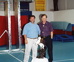 Two men beside a sculpture model at an exhibition booth