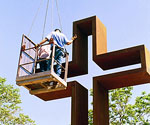 Worker in an elevated work basket beside the cross's upper arm