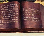 Detail of the inscribed open-Bible pages beneath The Great Commission® globe