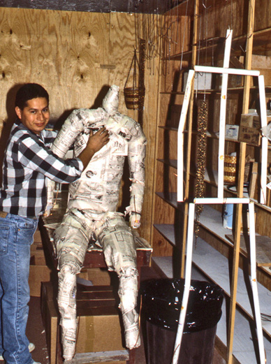 Sculptor beside the seated figure's unfinished armature