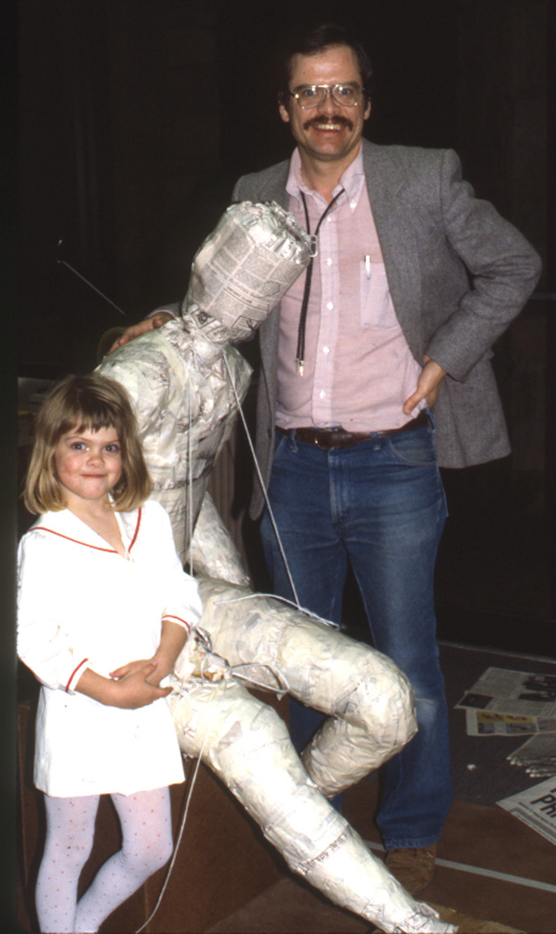 Man and child beside the unfinished seated figure model