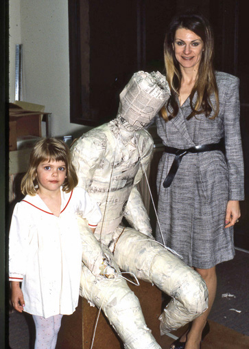 Woman and child standing beside the seated figure armature