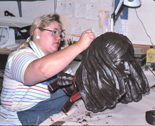 Worker refining the long hair on a dark wax head