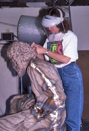 Worker applying surface treatment to the seated figure's head