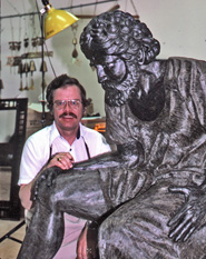 Max Greiner seated beside the large wax figure in the workshop
