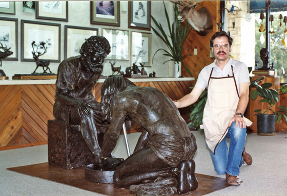 Artist kneeling beside the completed wax foot-washing composition