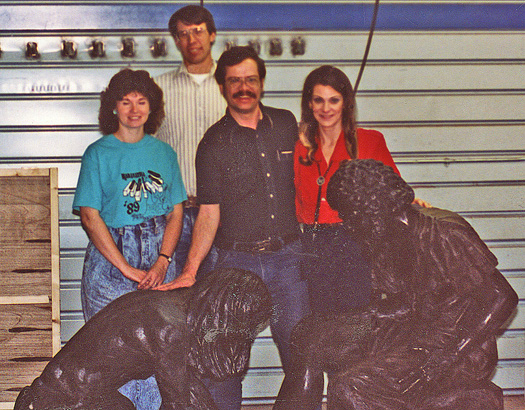Four people posing behind Divine Servant® in a workshop