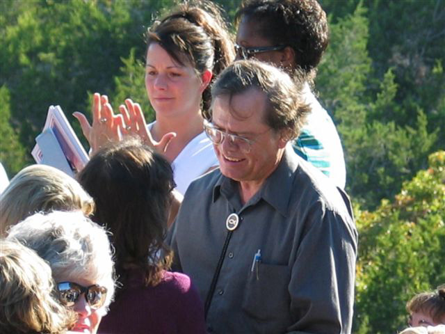 Close view of Max Greiner praying with a group of visitors
