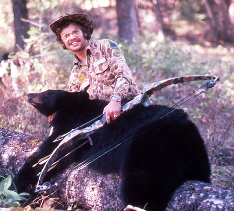 Max Greiner with a bow beside a black bear outdoors