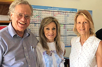 Three people posing together indoors, including office manager Debby Schmidt